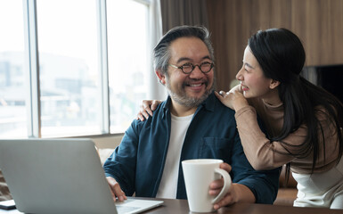 Middle-aged Asian Wife encourages cheerful husband to work.