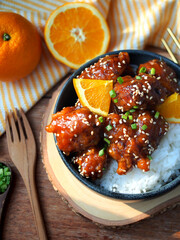 Orange chicken, Deep fried chicken breast with orange juice sauce on rice in top view.