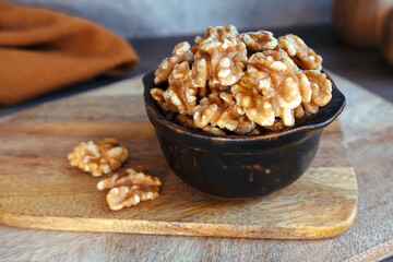 Black bowl with dried fruit and nuts on wooden board