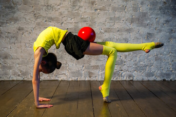 Young gymnast girl stretching and training with a red ball. Sport and healthy lifestyle concept