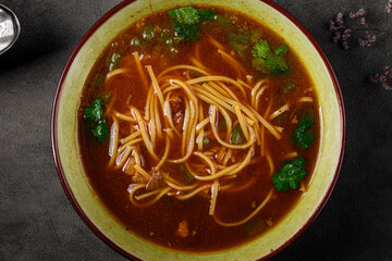 Closeup on asian noodle soup with parsley on grey background