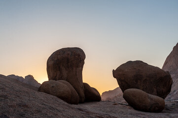 Fototapeta na wymiar Giant boulders contrast with a yellow glow of the setting sun. Spitzkoppe area, Namibia.