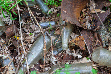 Rusty old tin cans and glass bottles decaying in at dump site in the forest.