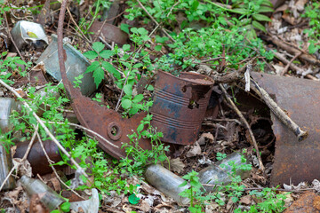 Rusty old tin cans and glass bottles decaying in at dump site in the forest.