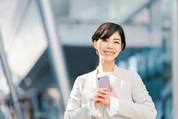 スマートフォンを持つスーツ姿の女性