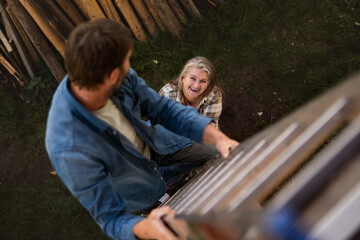 High angle view of mature man climbing up the ladder looking at his wife