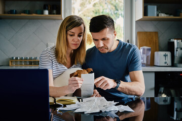 Man and woman checking payment bills in the kitchen at home. Planning family budget. Couple...