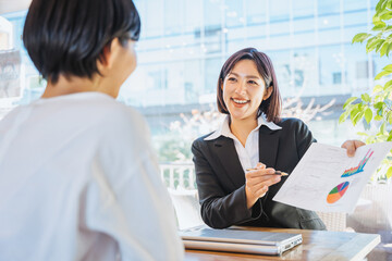 資料を見せて説明する女性（ビジネスイメージ）