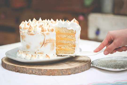 Person serving a slice of meringue and lemon curd cake