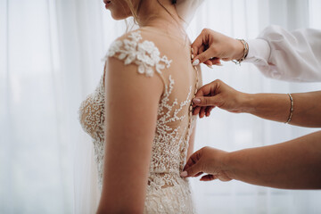 female hands fasten a button on a wedding dress