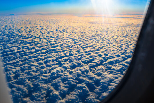 Flight to Sunrise / View from plane window to rising sun above blanket of clouds (copy space)