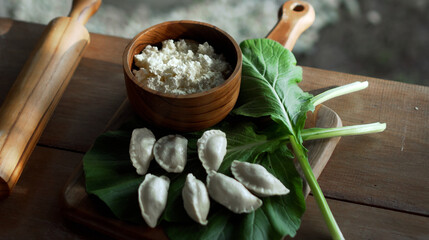 Fototapeta na wymiar Russian fresh handmade dumplings lying on a wooden table on a cutting board with cottage cheese in a wooden plate and spinach