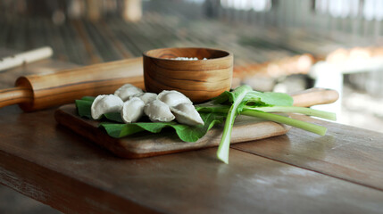 Russian fresh handmade dumplings lying on a wooden table on a cutting board with cottage cheese in...