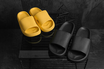 Two pairs of yellow and black Sandals shoes. Black and yellow flip flops on dark black background.