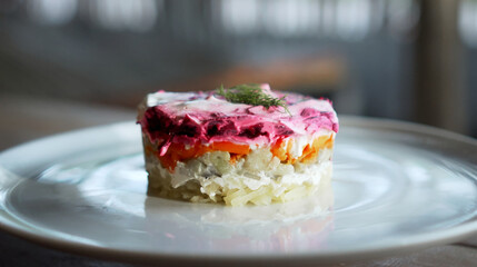 Traditional Russian salad with beetroot and herring vegetables, lying on a wooden table in a white plate