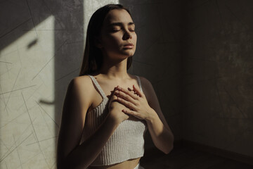 Serene woman breathing with closed eyes and relaxing while doing yoga and practicing stress relief...