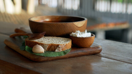Traditional Russian fresh hot soup borsch with beetroot, red color, with sour cream and fresh bread in a wooden plate standing on a wooden table