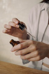 Crop woman with pipette and glass bottle of serum for facial beauty routine and daily skin care 