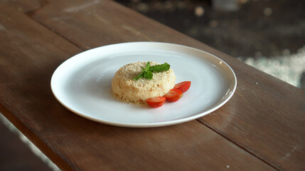 Little napoleon cake with strawberries on top standing on a white plate