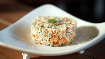 Traditional Russian fresh olivier salad lying on a wooden table