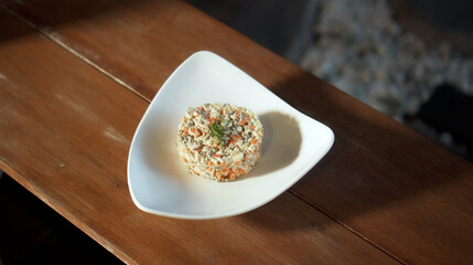 Traditional Russian fresh olivier salad lying on a wooden table