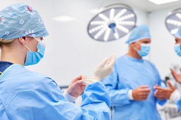 Young woman as a surgeon puts on disposable gloves