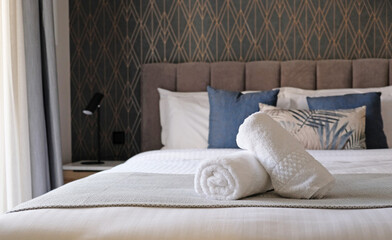 Comfortable bed with towels in hotel bedroom decoration in cozy style after room service ready for...