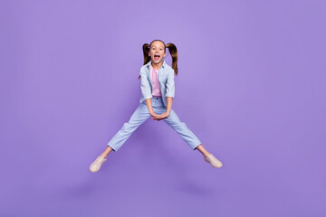 Fototapeta na wymiar Photo of impressed pretty small schoolgirl dressed jeans shirt jumping high isolated violet color background