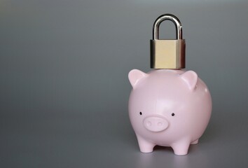 Padlock on top of piggy bank with copy space. Confiscation, account freeze, financial embargo.