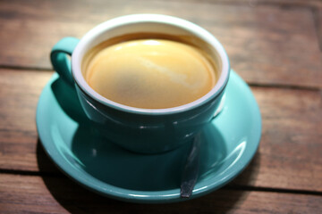 Hot black coffee or Americano in blue ceramic cup on wooden table background. 