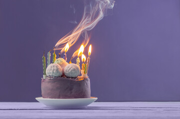 purple birthday cake with burning candles on violet  background