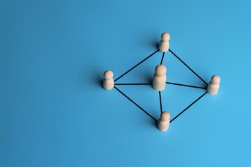 Wooden dolls connected by lines with copy space. Leadership, support, teamwork, networking concept