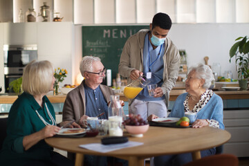 Group of cheerful seniors enjoying breakfast in nursing home care center.