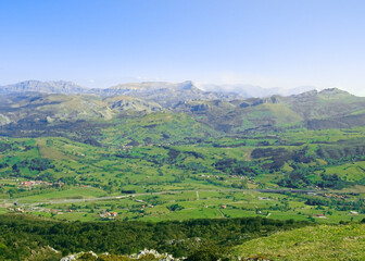 Fototapeta na wymiar Views of the green Pas region valleys (Valles Pasiegos) and its peaks: Fraile peak (Pico Fraile) and Castro Valnera peak (Pico Castro Valnera). At Peña Cabarga Llen peak in Santander, Cantabria.