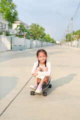 Asian little young girl child skating unsafe without protection on skateboard at the street