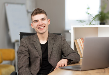 young cheerful programmer working in office on laptop