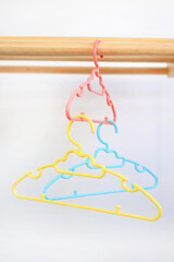 Colored plastic Clothes Hangers on wooden clothes line against white background