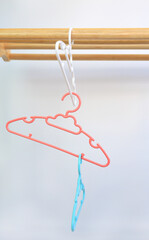 Colored plastic Clothes Hangers on wooden clothes line against white background
