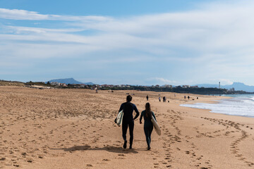 Couple retires after their day of surfing on Beach of the Chambre D'Amour. Biarritz