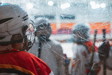 Children's ice hockey. A child hockey player in a protective uniform on the glass side of the ice field.