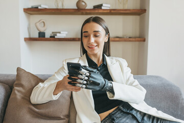 A woman with a bionic prosthetic arm holds a mobile phone in her hands, communicates on social...