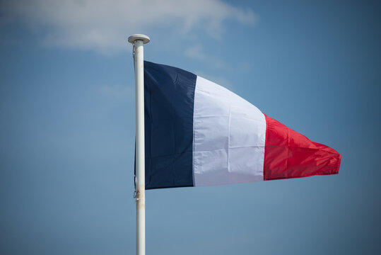 Closeup of french flag floating on blue sky background
