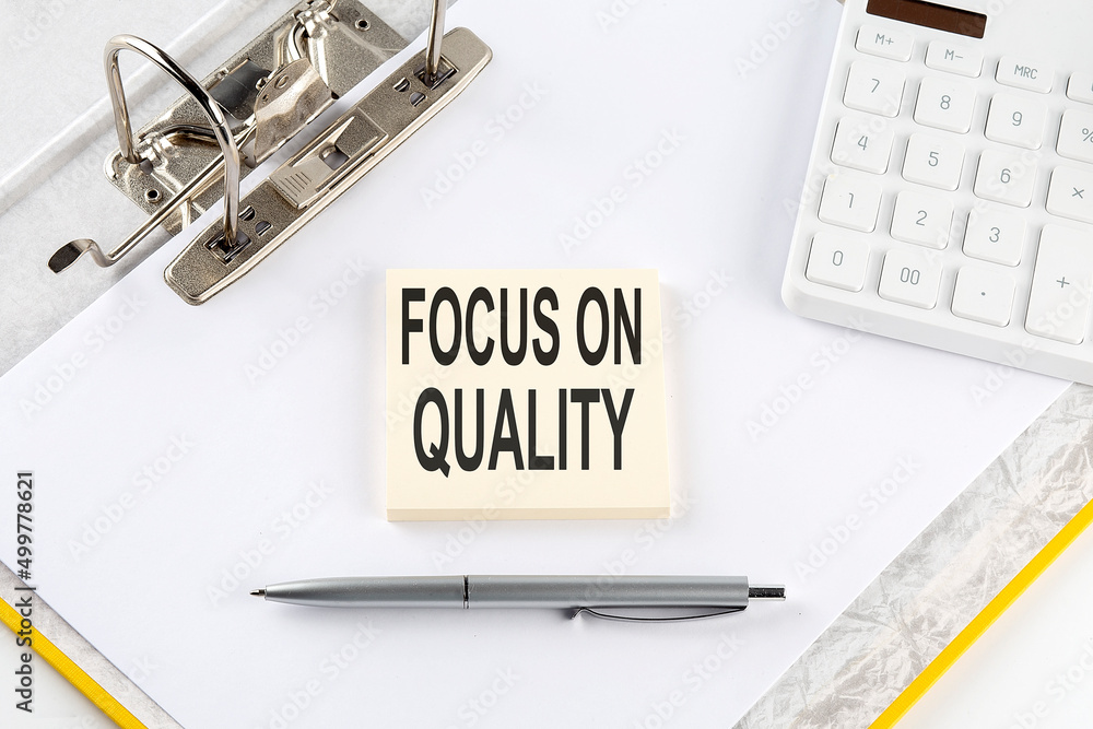 Poster focus on quality - business concept, message on the sticker on folder background with calculator