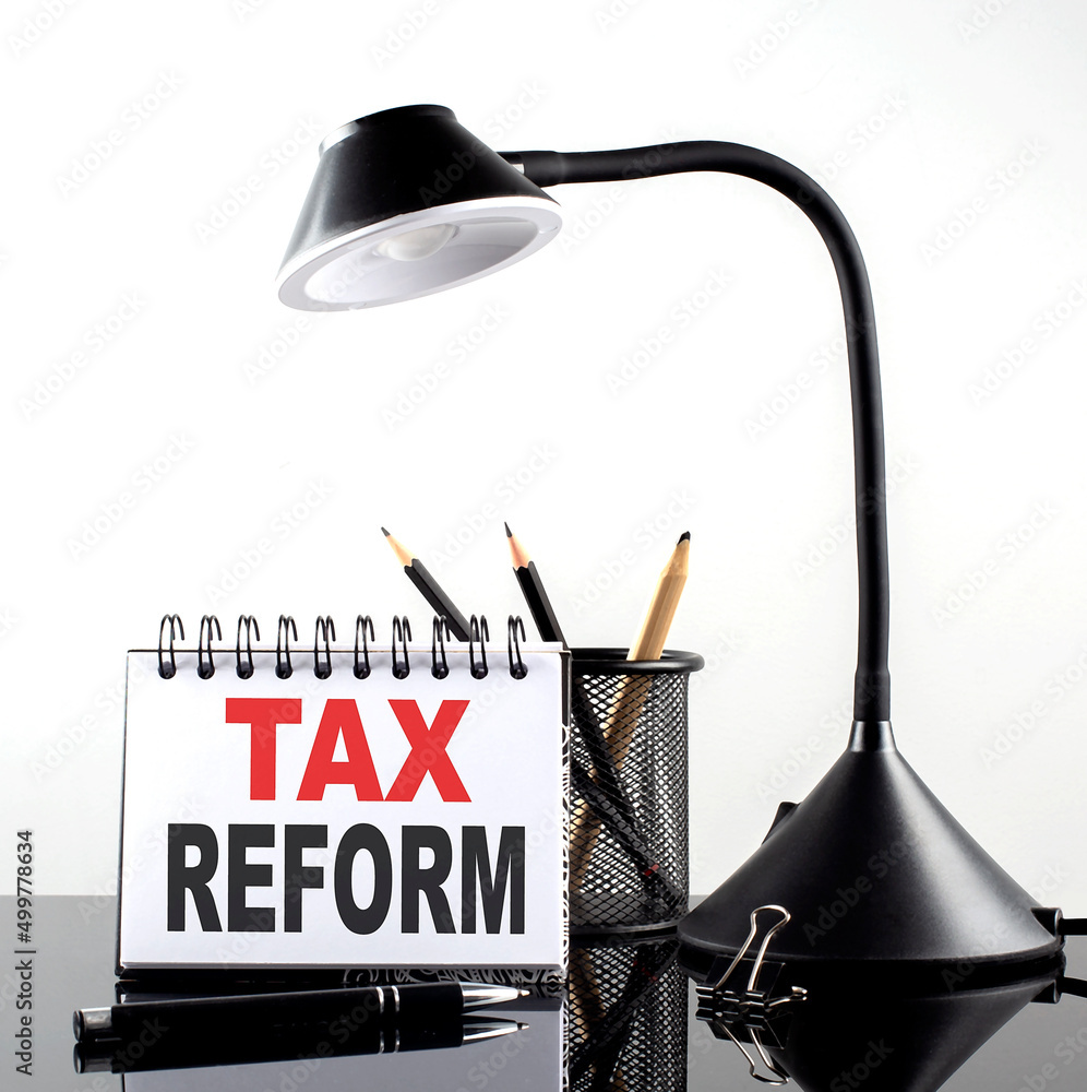 Poster tax reform text on notebook with pen and table lamp on the black background