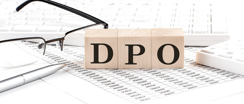 DPO - Days Payable Outstanding written on wooden cube with keyboard , calculator, chart,glasses.Business concept