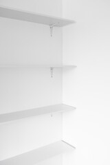 minimalist white wall with white shelves in a niche, modern interior design and simple home improvements