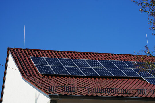 Solar Module auf einem Dach im Sonnenschein. Bei dem blauen Himmel kann im Fr&uuml;hling viel Strom produziert werden. Das Dach wird links und rechts von hohen Blitzableitern gesch&uuml;tzt