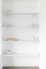 minimalist white wall with shelves in a niche with white plant pots and wooden tray, modern interior design and simple home improvements