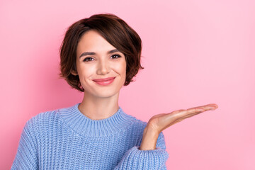 Portrait of cute funny positive female hold hands present new product promoter isolated on pink color background