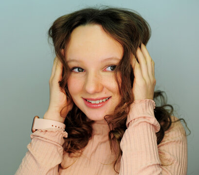 a girl in a make-up studio tinager in pink golf smiles happy with a new makeup in her eyes reflects a lamp for photography gently painted eyelashes and lips hair blonde girl 10-13 years old.
